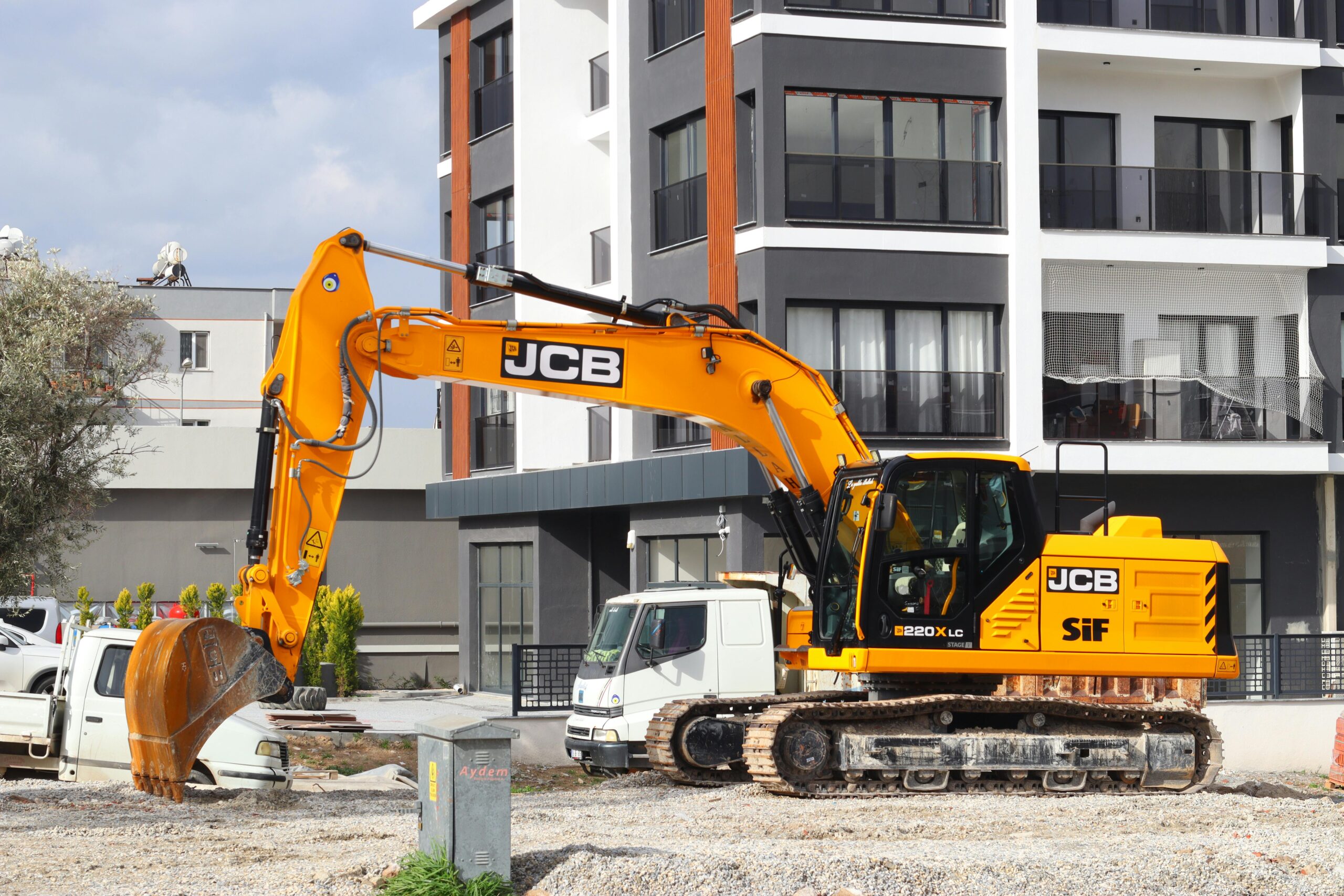 Home A yellow excavator operating at a city construction site in front of modern buildings.